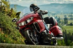 a red motorcycle parked on the side of a road with mountains in the back ground