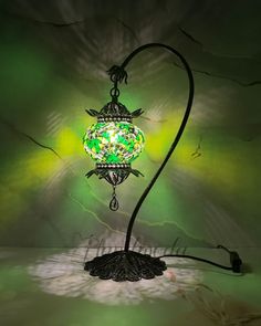 a green lamp sitting on top of a table next to a black corded light