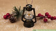 an old fashioned lantern is sitting next to some berries and pineconi on the table