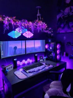 a computer desk topped with monitors and speakers in a room filled with purple lights at night