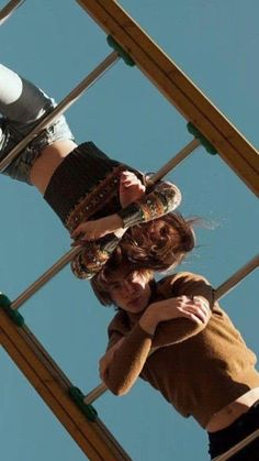 two young women standing on top of a metal structure with their arms around each other