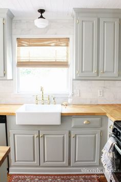 a kitchen with gray cabinets and white counter tops, an area rug on the floor