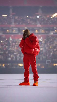 a man in red is standing on the stage talking on his cell phone while wearing an orange outfit