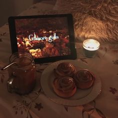 a table topped with donuts next to a lit candle and tablet computer screen on top of it