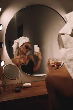 a woman taking a selfie in front of a mirror with a towel on her head