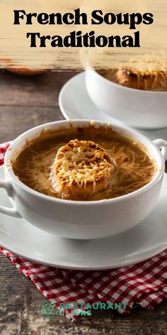 two white bowls filled with french soup on top of a wooden table next to a red and white checkered napkin