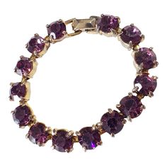 This vintage women's tennis bracelet showcases a 14+ carat purple amethyst gemstone, which has been lab-created and is perfectly round in shape. The gemstone is set in a gold tone metal with slight signs of wear, stone with minor loss,, but is still in overall good condition. Measuring 6.75 inches in length and 0.25 inches in height. Elegant Round Amethyst Crystal Bracelet, Elegant Round Purple Crystal Bracelet, Elegant Purple Round Crystal Bracelet, Classic Purple Tennis Bracelet As A Gift, Classic Purple Tennis Bracelet As Gift, Classic Purple Tennis Bracelet Perfect For Gifts, Purple Tennis Bracelet For Anniversary, Elegant Gold Amethyst Crystal Bracelet, Purple Round Bracelets For Anniversary