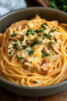 a bowl filled with pasta and sauce on top of a wooden table next to parsley