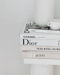 three books stacked on top of each other next to a white cup and saucer