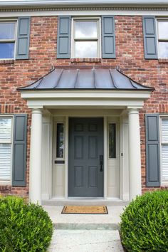 the front door of a brick house with shutters