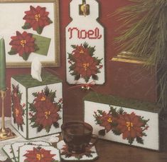 cross - stitch christmas decorations with poinsettis and candlesticks on a table