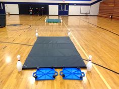 two bowling pins sitting on top of a hard wood floor next to blue and white cones