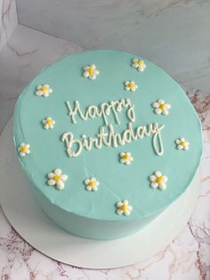 a blue birthday cake with white flowers and the words happy birthday on it's frosting