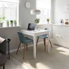 a white table with two blue chairs and a laptop on it