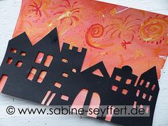 a paper cut out of the shape of a house with an orange sky in the background