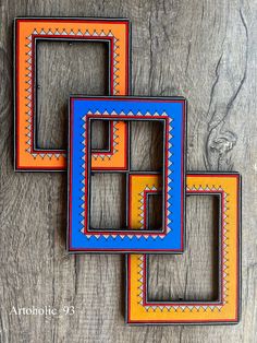 three colorful frames sitting on top of a wooden table