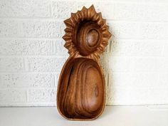 a wooden vase sitting on top of a white table next to a brick wall with a sunflower