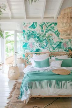 a tropical bedroom with palm leaves on the wall and green bedding in front of it