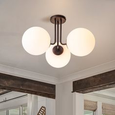 three lights are hanging from the ceiling in a room with white walls and wood beams