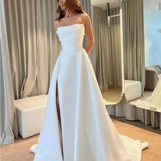 a woman in a white wedding dress standing next to a mirror