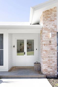 the front door of a house with two glass doors and a brick pillar on the porch