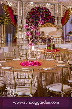 an elaborately decorated banquet hall with gold chairs and pink flower centerpieces on the tables