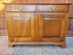 a wooden cabinet with two doors on the front and one door open, sitting on a brick patio