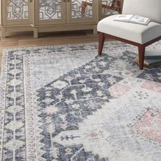 a large area rug with an ornate design on the front and side, along with a white chair