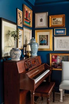 there is a piano in the corner of this room with many pictures on the wall