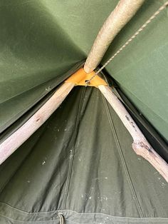 the inside of a green tent with wood sticks sticking out of it's side