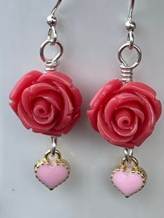 These serene Coral Rose Earrings are as soothing as the oceans waves. 14mm coral polyresin rose beads accented with a 8mm light pink heart charm. All hand wire wrapped in silver plated wire. 1.75 inches long. Let the coral reefs beckon to you. Sterling Silver Jewelry With Pink Heart Beads, Pink Rose Design Flower Earrings For Valentine's Day, Pink Sterling Silver Heart Earrings For Mother's Day, Coral Jewelry Gift With Ear Wire, Coral Jewelry With Ear Wire For Gift, Pink Nickel-free Heart Earrings For Valentine's Day, Pink Rose Design Earrings For Valentine's Day, Rose Earrings For Valentine's Day, Adjustable Rose Red Jewelry For Valentine's Day