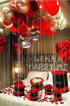 a bed topped with lots of red and white heart shaped balloons next to a cake