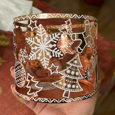 a hand holding a glass with christmas decorations on it