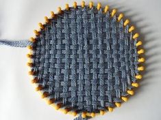 a close up of a woven object on a white tablecloth with yellow and gray pins