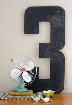 the letter e is next to a fan on a wooden table with cups and saucers