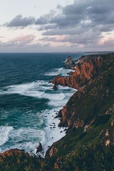 an ocean view with waves crashing on the rocks