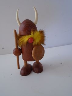 a wooden toy with horns and feathers holding a stick