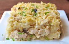 a white plate topped with rice covered in meat and veggies on top of a wooden table