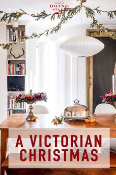 a wooden table topped with white chairs next to a christmas tree