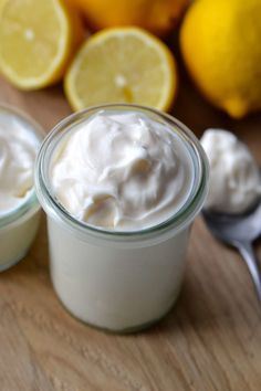 two small jars filled with yogurt next to lemons