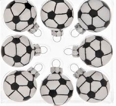 six soccer ball ornaments are in a clear box with white and black designs on them