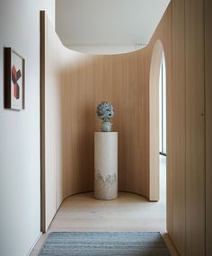 a white vase sitting on top of a wooden floor next to a doorway in a room