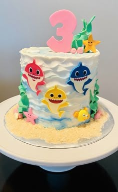 a birthday cake decorated with different types of shark and sea creatures on top of a white plate