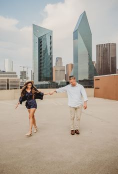 a man and woman holding hands in front of tall buildings