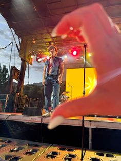 a hand is pointing at an object on the stage that appears to be playing music