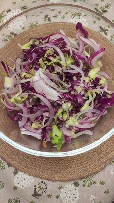 a glass bowl filled with red cabbage and lettuce on top of a table