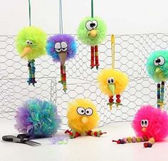 several different colored birds hanging from hooks on a wire net with scissors and other items in front of them