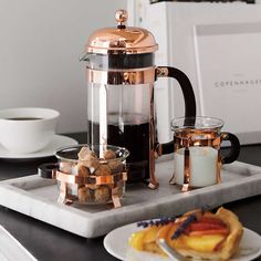 a tray with some food on it next to a cup of coffee and a candle