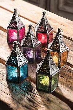 four colorful lanterns sitting on top of a wooden table next to each other with lights inside them