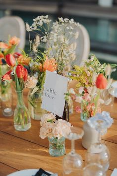 there are many vases with flowers in them sitting on the dining room table at this wedding reception